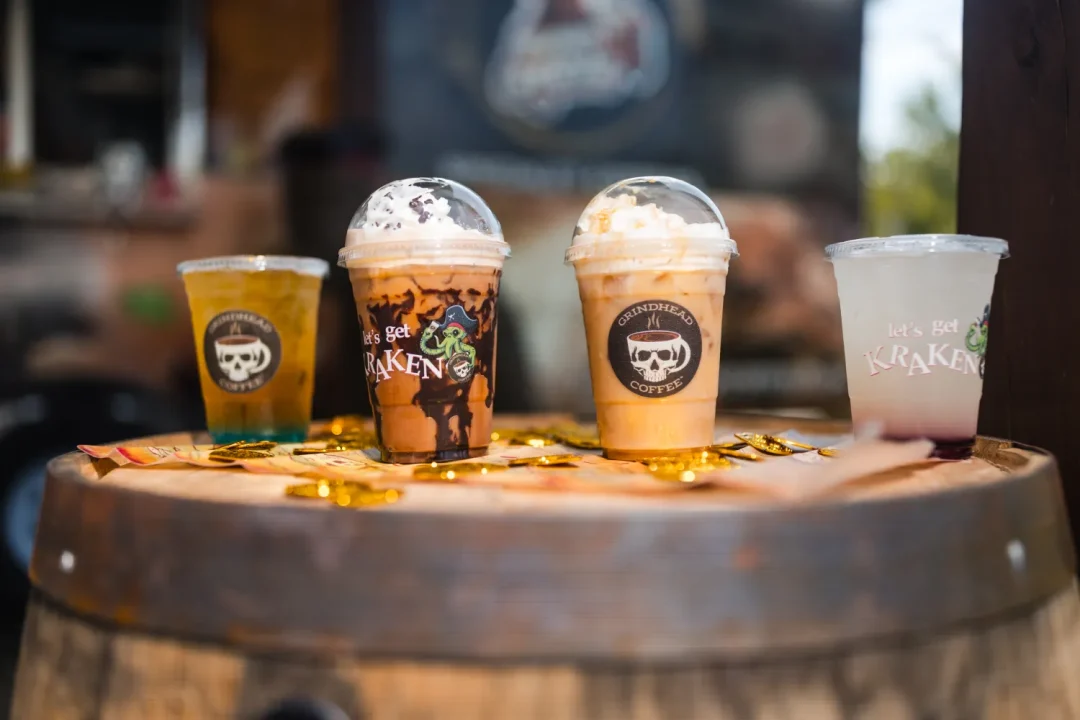 food-13 Four assorted cold drinks with whipped cream on a barrel, surrounded by gold coins and pirate decor.