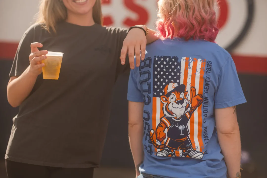 food-18 Two people, one holding a drink, stand together; one has a cartoon tiger on their blue t-shirt.