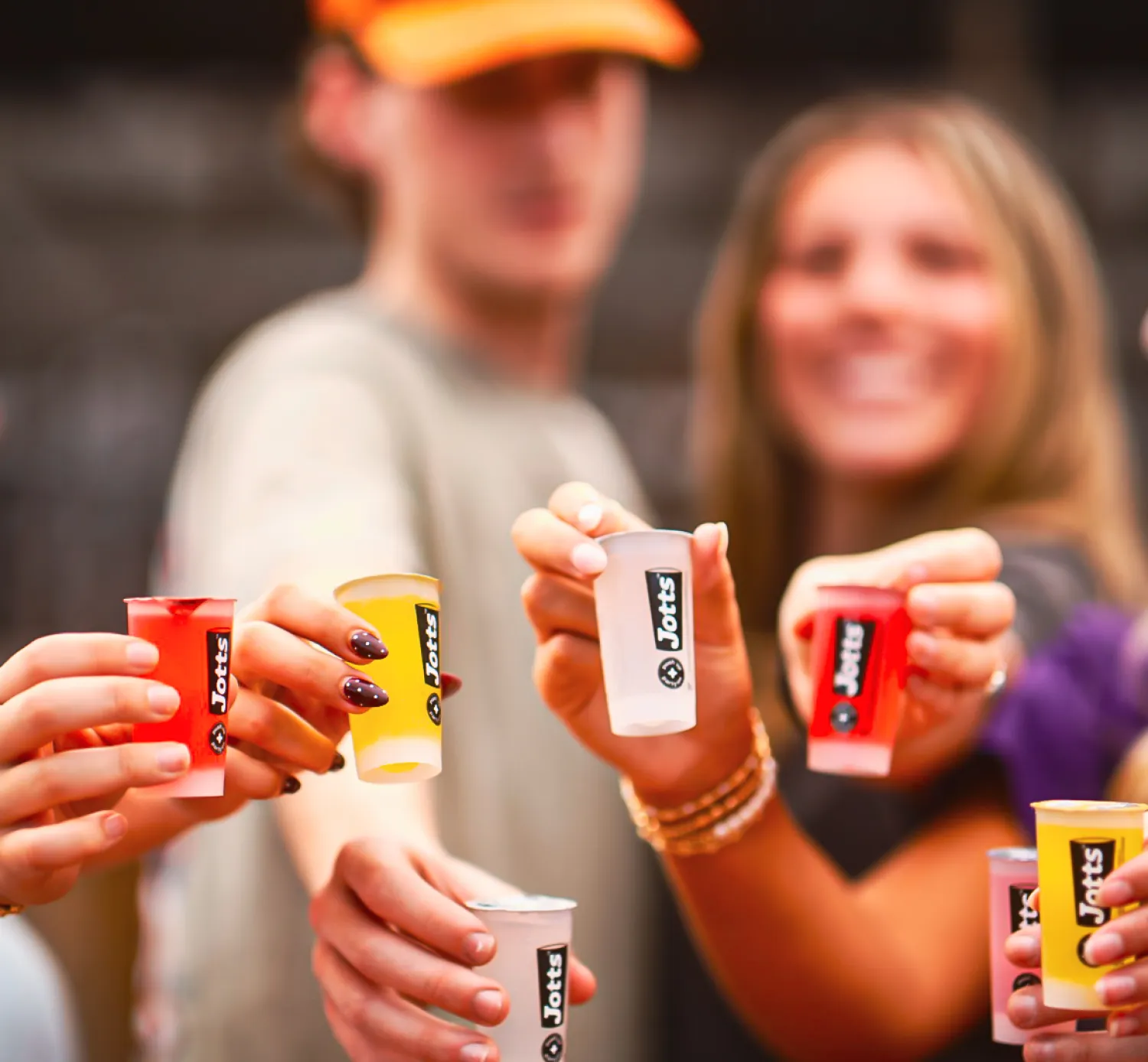 People holding colorful Jolly Jorts gelatin shot cups, smiling and toasting together in a group.