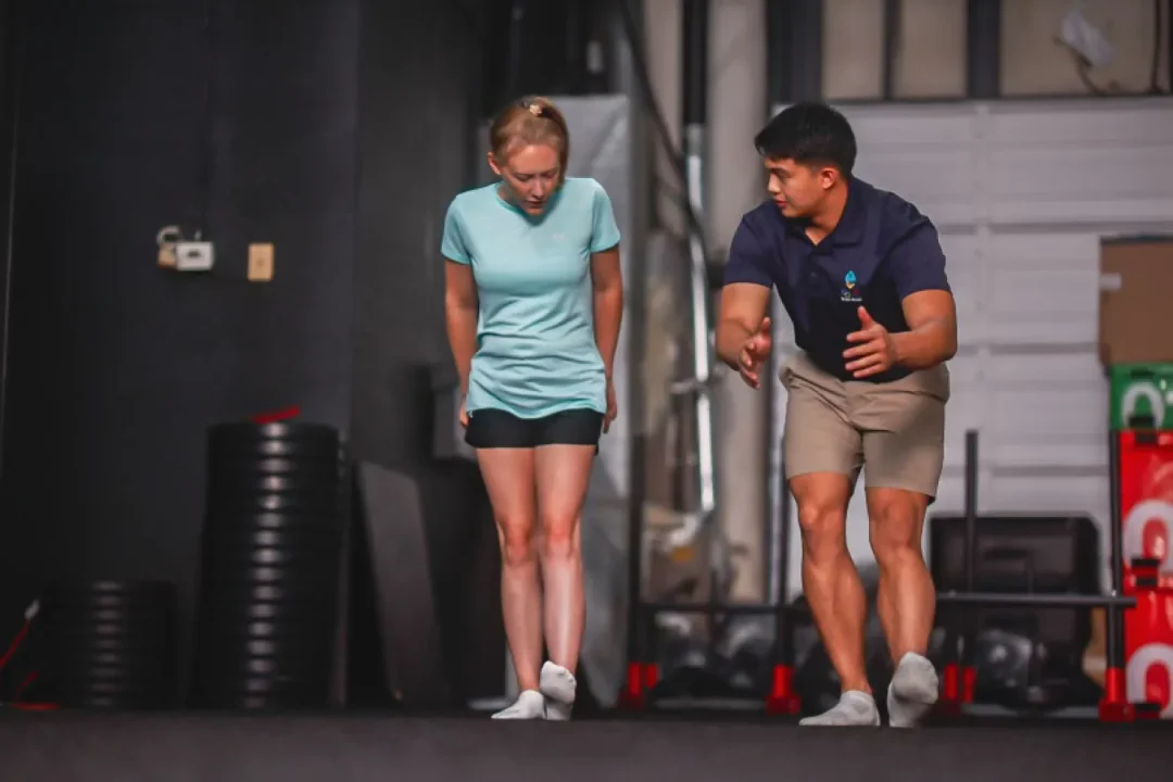 health-wellness-18 A woman and a man in athletic wear balance on one leg indoors, focusing on their movements.