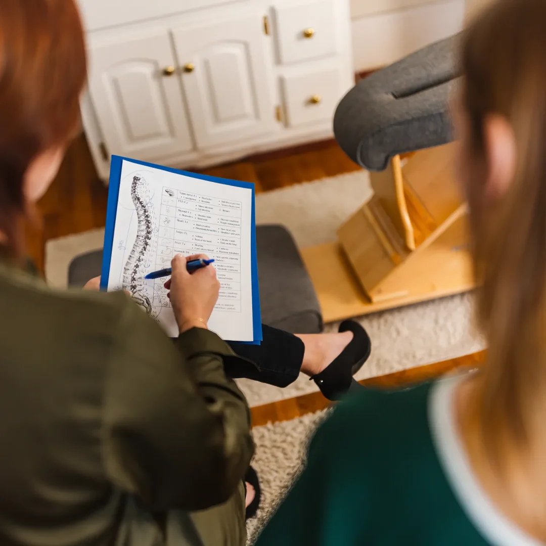 health-wellness-21 Two people review a spinal diagram on a clipboard in a medical or chiropractic office.
