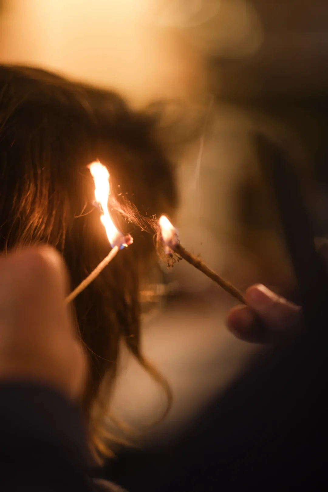 professional-4 Two sticks with flames are held near someone’s hair, possibly for a traditional hair treatment.