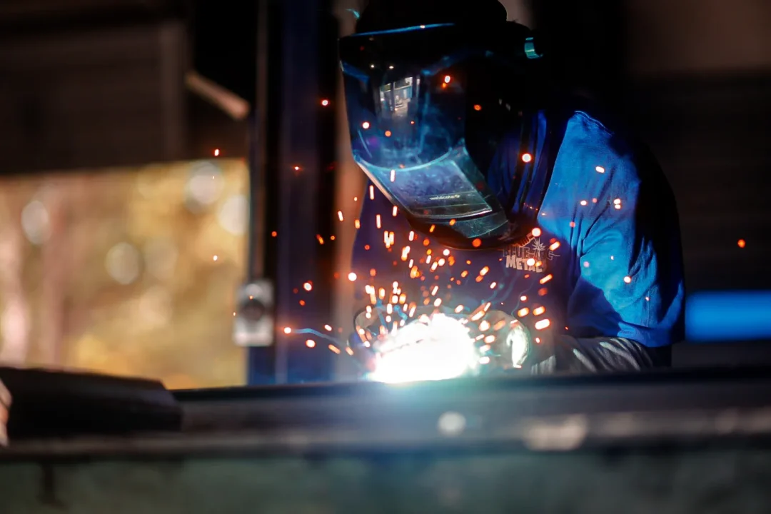 trades-11 A person in safety gear welding metal, with bright sparks flying around.