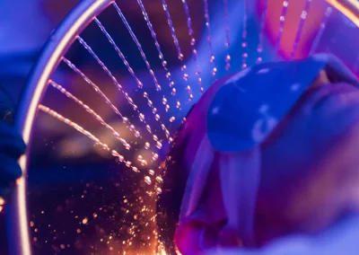 Person wearing an eye mask under a circular light with glowing lines and sparkles in a blue-purple setting.