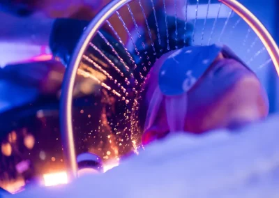 Person with an eye mask under colorful lights, viewed through a circular glass with water droplets.