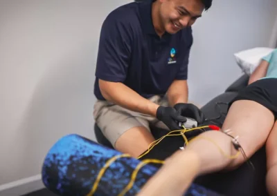 A therapist applies electrical stimulation pads to a patient’s leg during a physical therapy session.