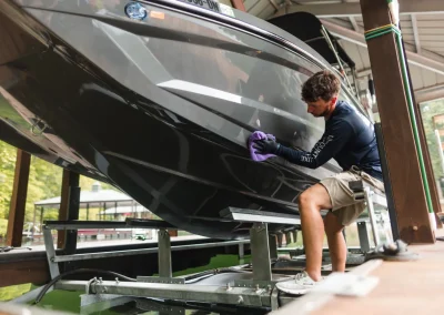 A person cleaning the hull of a boat while it is docked on a lift.