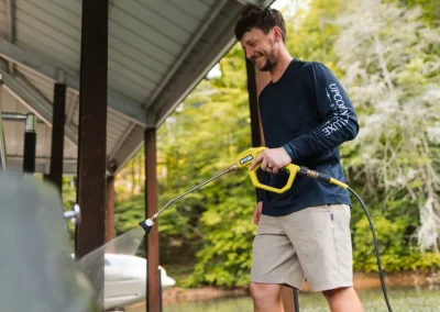 A man using a Ryobi pressure washer to clean a surface on a wooden deck.