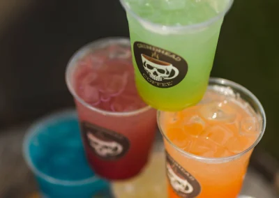 A stack of five colorful iced drinks in clear plastic cups with Grindhead Coffee logos.