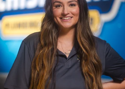 Smiling woman with long brown hair standing in front of a Chisholm logo.