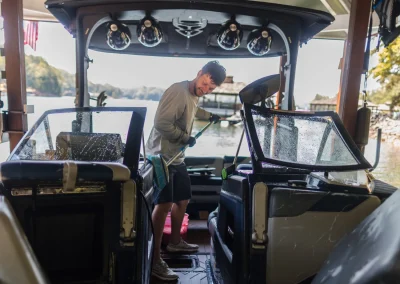 A man cleans the interior of a boat with a long-handled brush.