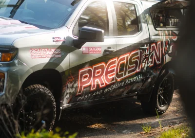 Precision Pest and Wildlife Removal truck parked on a residential street.